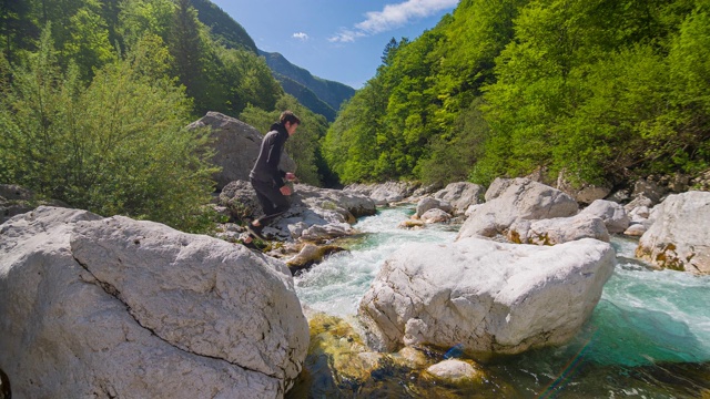 年轻人在雄伟的风景中跳过山河视频素材