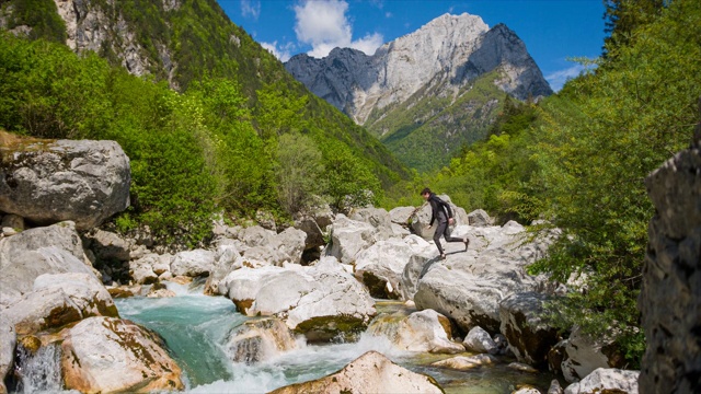 徒步旅行者在山中过河，跳过水视频素材