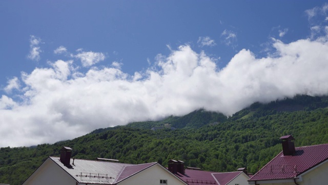 多云的天空越过岩石山峰，时光流逝的看法。索契Estosadok村，白色的云覆盖着冰雪山峰Aibga山脊。夏日山顶上的云景视频素材