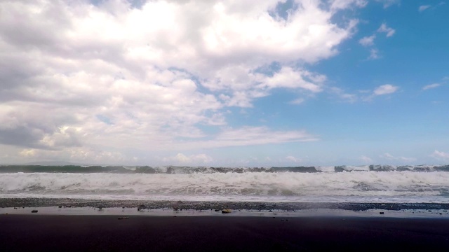 巨大的海浪拍打着黑色火山海滩的海岸。慢动作的观点。视频素材