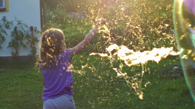 小女孩玩巨大的肥皂泡在日落背光的观点视频素材