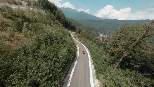 从运动FPV无人机在夏季高地蜿蜒的道路。一辆敞篷车在索契蜿蜒的道路上行驶。在山上旅行，覆盖夏季森林空中电影的观点视频素材