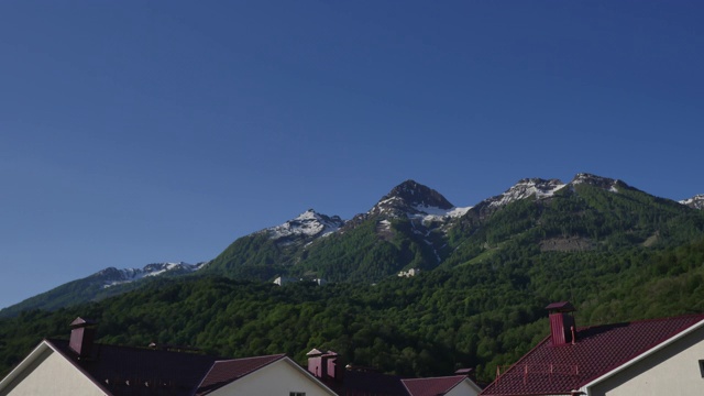 令人惊叹的日出时间在山脊覆盖着绿色的森林和雪，屋顶的背景。索契Estosadok村Aibga山脊的清晨日出视频素材