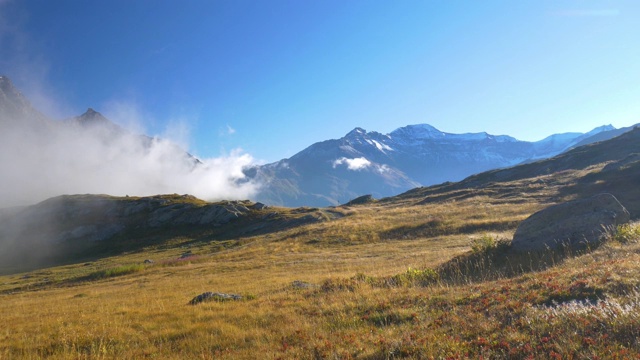 高山景观晨雾薄雾和云山谷山下的阿尔卑斯山脉和山峰，映衬着清澈的蓝天。视频素材