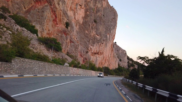 在海岸和岩石山脉之间的一条蜿蜒的道路视频素材