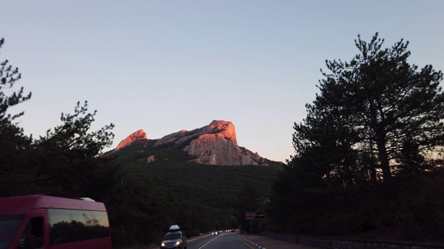 在一个温暖的夏夜，道路的傍晚风景穿过山脉视频素材