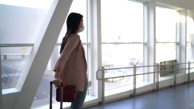 年轻的女旅行者在机场走着，戴着口罩视频素材