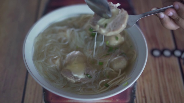 在街头小吃市场的餐桌上吃着肉丸和汤面视频素材