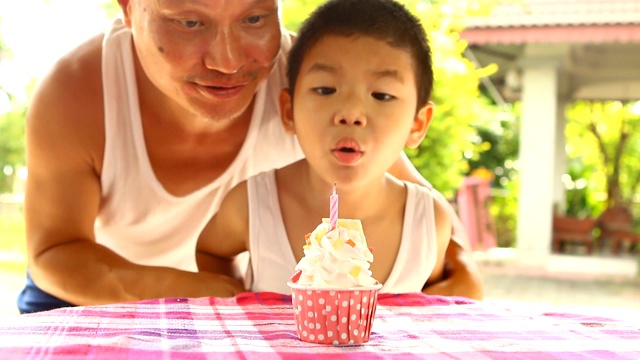 泰国小孩唱歌，吹灭杯子蛋糕上的蜡烛视频素材