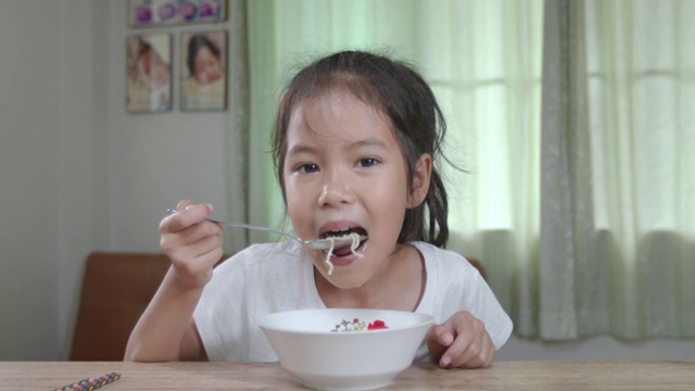 可爱的亚洲小女孩在家里用筷子吃美味的方便面。慢动作镜头。视频素材