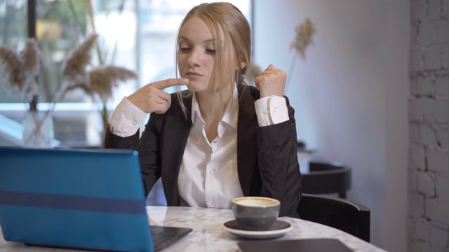 成功年轻女商人的休息时间。肖像自信的女人专注坐在桌子上的咖啡和上网的笔记本电脑。漂亮的黑发女士过度工作。视频素材