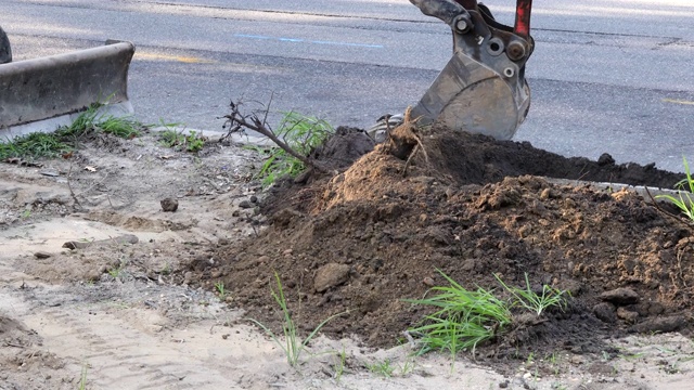 市政拖拉机与挖土机在道路上工作，挖掘机在开挖坑施工视频素材