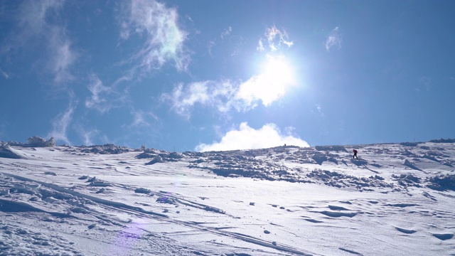 4K爬山者的小身影在雪山上，云在天空中快速移动视频素材