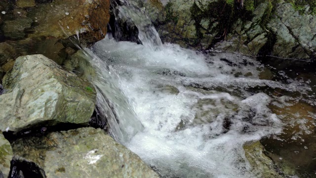 瀑布和小溪在绿色的森林岩石。小溪在岩石、巨石和植物之间流动视频素材