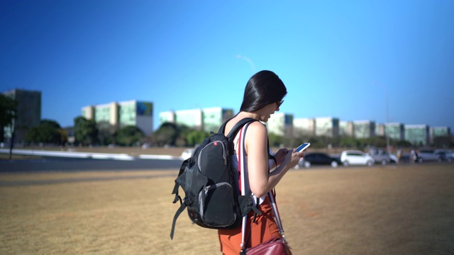 在巴西，一个年轻的女旅行者一边走路一边使用手机视频素材