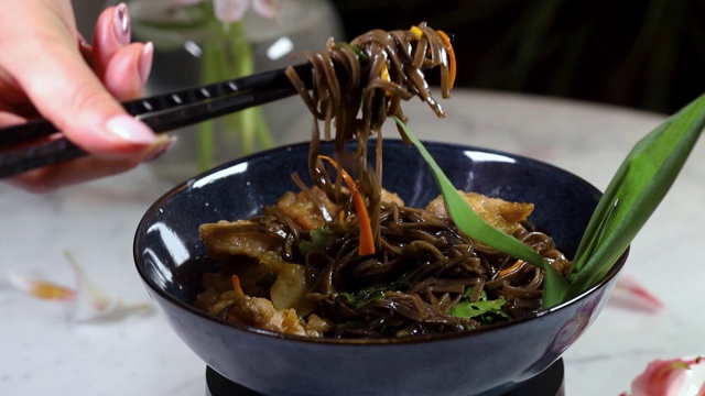 日本料理:黑碗炒荞麦面和蔬菜。美味，营养的亚洲食物视频素材