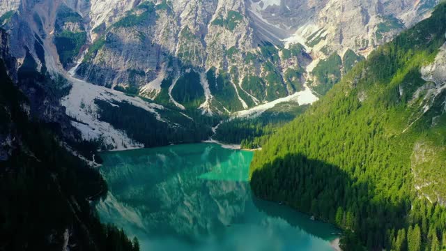 蓝色的湖面，水面反射着阳光。景观与森林和山周围的湖在航空视图与无人机4K视频素材