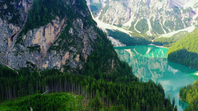 蓝色的湖面，水面反射着阳光。景观与森林和山周围的湖在航空视图与无人机4K视频素材