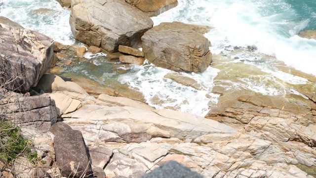 汹涌的海浪和水花拍打在带有海水泡沫的岩石海滩上。湛蓝的海水，海边，石头海岸视频素材