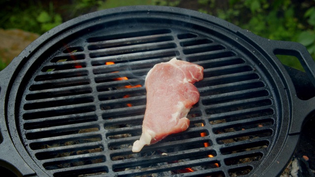 一个男人的手把猪肉放在烤架上。视频素材