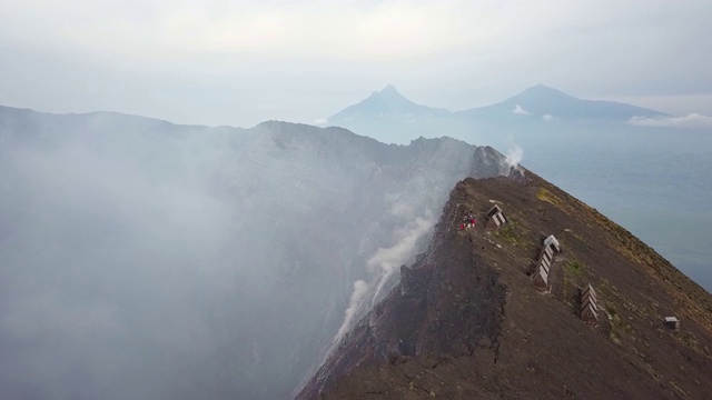 人们站在尼拉贡戈活火山的火山口边缘，熔岩湖喷出浓烟视频下载