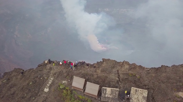 人们站在尼拉贡戈活火山的火山口边缘，熔岩湖喷出浓烟视频下载