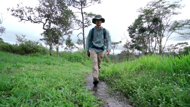 一幅英俊的蓄着胡须的徒步旅行者走在山间小道上的肖像视频素材