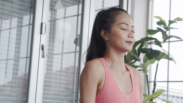 近距离观察美丽的亚洲女性在运动服做伸展瑜伽运动锻炼在一个垫子在客厅在家里。视频素材