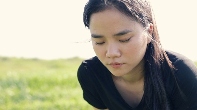 近距离观看亚洲女跑步运动员在有氧运动后疲惫地休息看镜头。视频素材