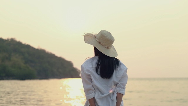 年轻的亚洲女人旅行者伸展双臂举起感觉放松享受假日，而站在海滩上。视频素材