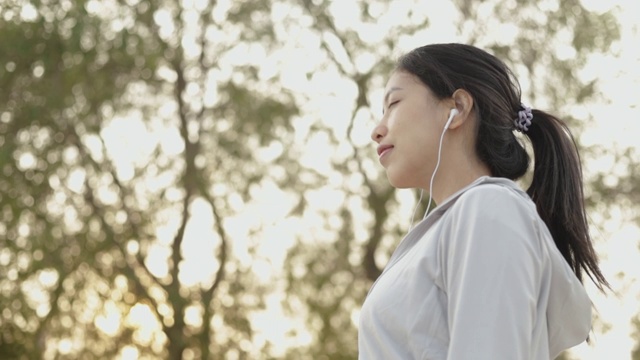 迷人的年轻亚洲女性跑步者站在海边放松的海滩上跑步后，健康的生活方式锻炼运动。视频素材