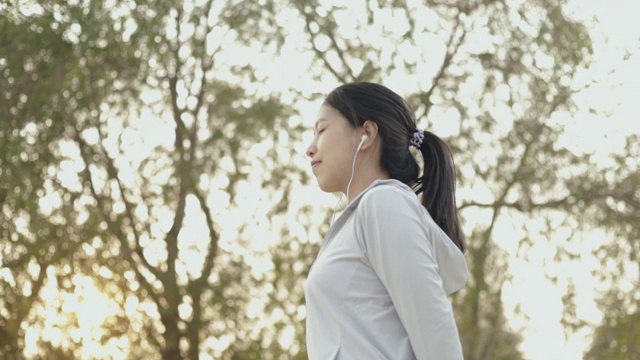 迷人的年轻亚洲女性跑步者站在海边放松在沙滩上跑步后。视频素材