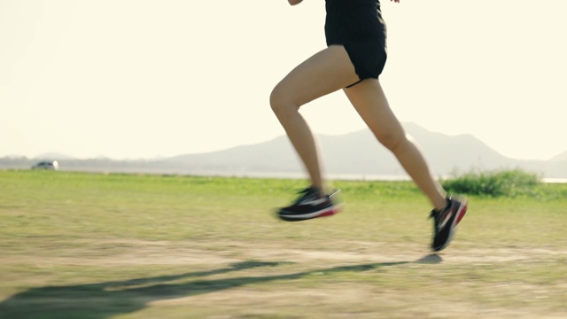 一名亚洲女跑步运动员在日落日出时进行训练。视频素材