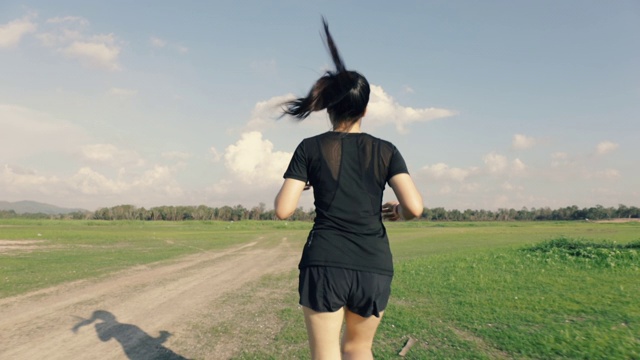 跟随拍摄的亚洲妇女跑在乡村道路在山景美丽的日落。视频素材