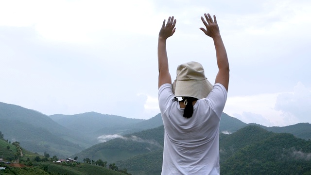 愉快的年轻女子与她的手臂伸展在山顶与天空的背景。成就与制胜理念。视频素材