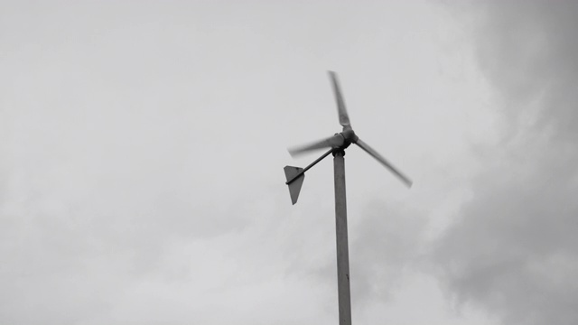 在阴云密布的雨季，风力涡轮机在空中旋转。绿色能源发电。视频素材