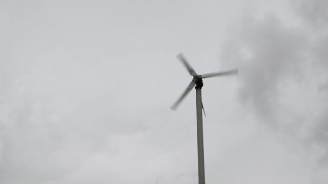 在阴云密布的雨季，风力涡轮机在空中旋转。绿色能源发电。视频素材