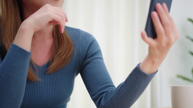 美丽的年轻亚洲女人做一个视频电话微笑和她的朋友和家人在家里交谈视频素材