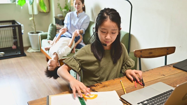 小学女孩学习视频在线课程在家里的客厅。视频素材