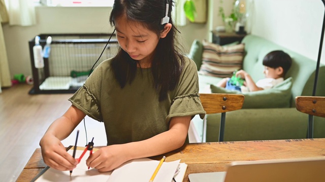 小学女孩学习视频在线课程在家里的客厅。视频素材