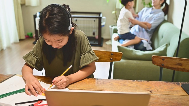 小学女孩学习视频在线课程在家里的客厅。视频素材