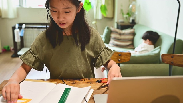 小学女孩学习视频在线课程在家里的客厅。视频素材