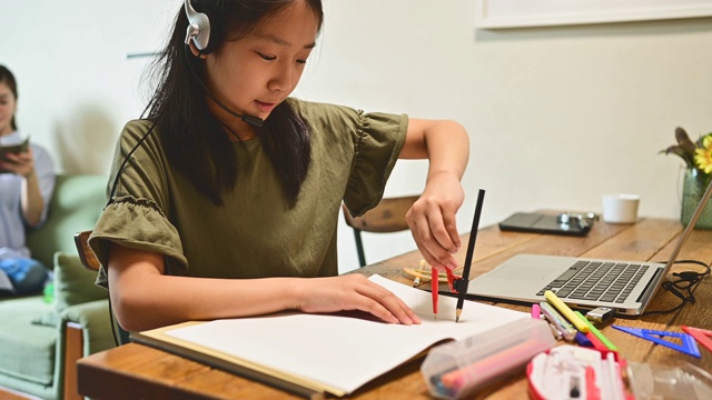 小学女孩学习视频在线课程在家里的客厅。视频素材