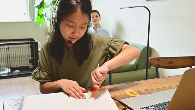 小学女孩学习视频在线课程在家里的客厅。视频素材