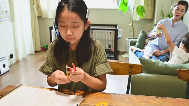 小学女孩学习视频在线课程在家里的客厅。视频素材