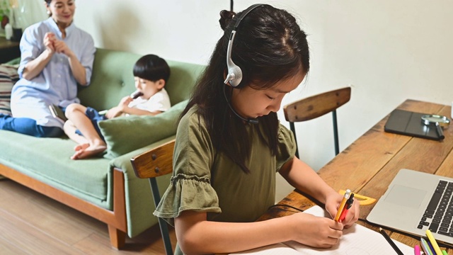 小学女孩学习视频在线课程在家里的客厅。视频素材