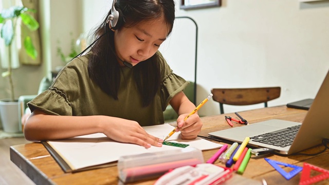 小学女孩学习视频在线课程在家里的客厅。视频素材