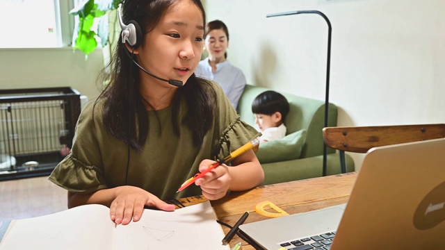 小学女孩学习视频在线课程在家里的客厅。视频素材