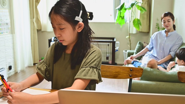 小学女孩学习视频在线课程在家里的客厅。视频素材