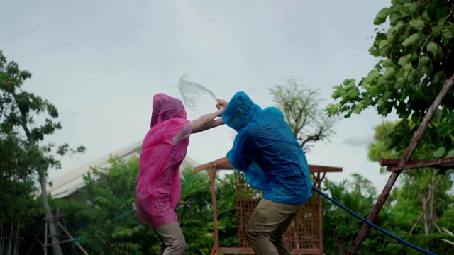 微笑的亚洲夫妇穿着雨衣在花园视频素材